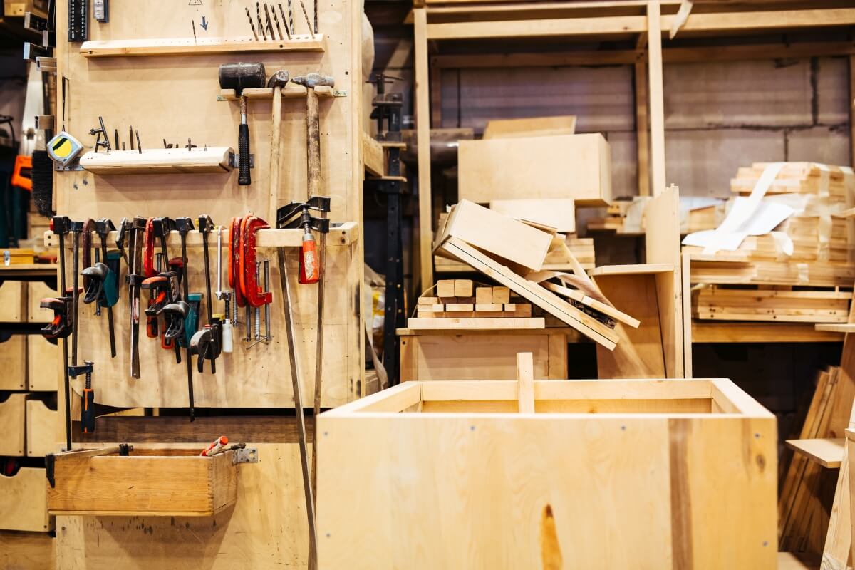 Warsztat pełen narzędzi, a na pierwszym planie stojaki warsztatowe ze sklejki.