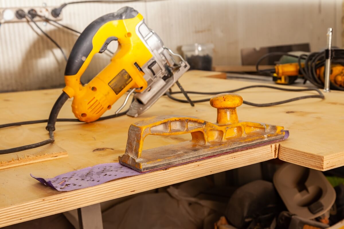 Na stole warsztatowym leżą narzędzia do obróbki sklejki na wymiar.