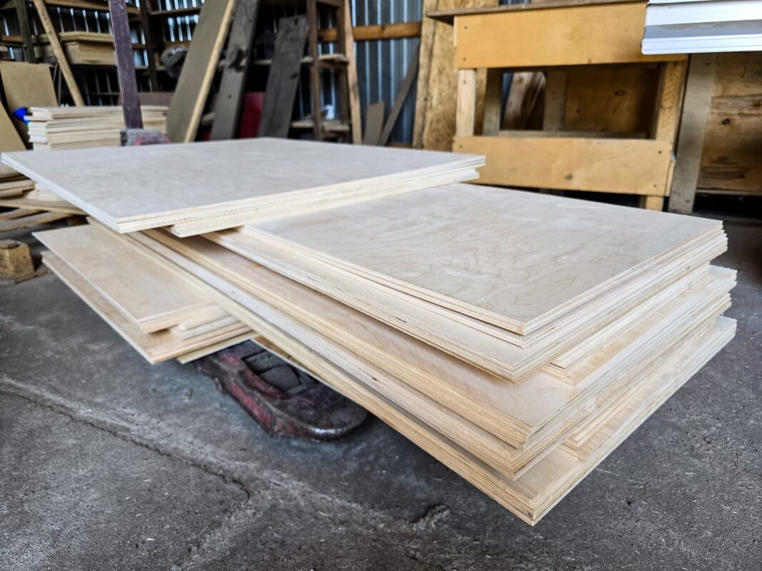 Stosy płyt leżące na podłodze warsztatu, z czego część to sklejka antypoślizgowa.